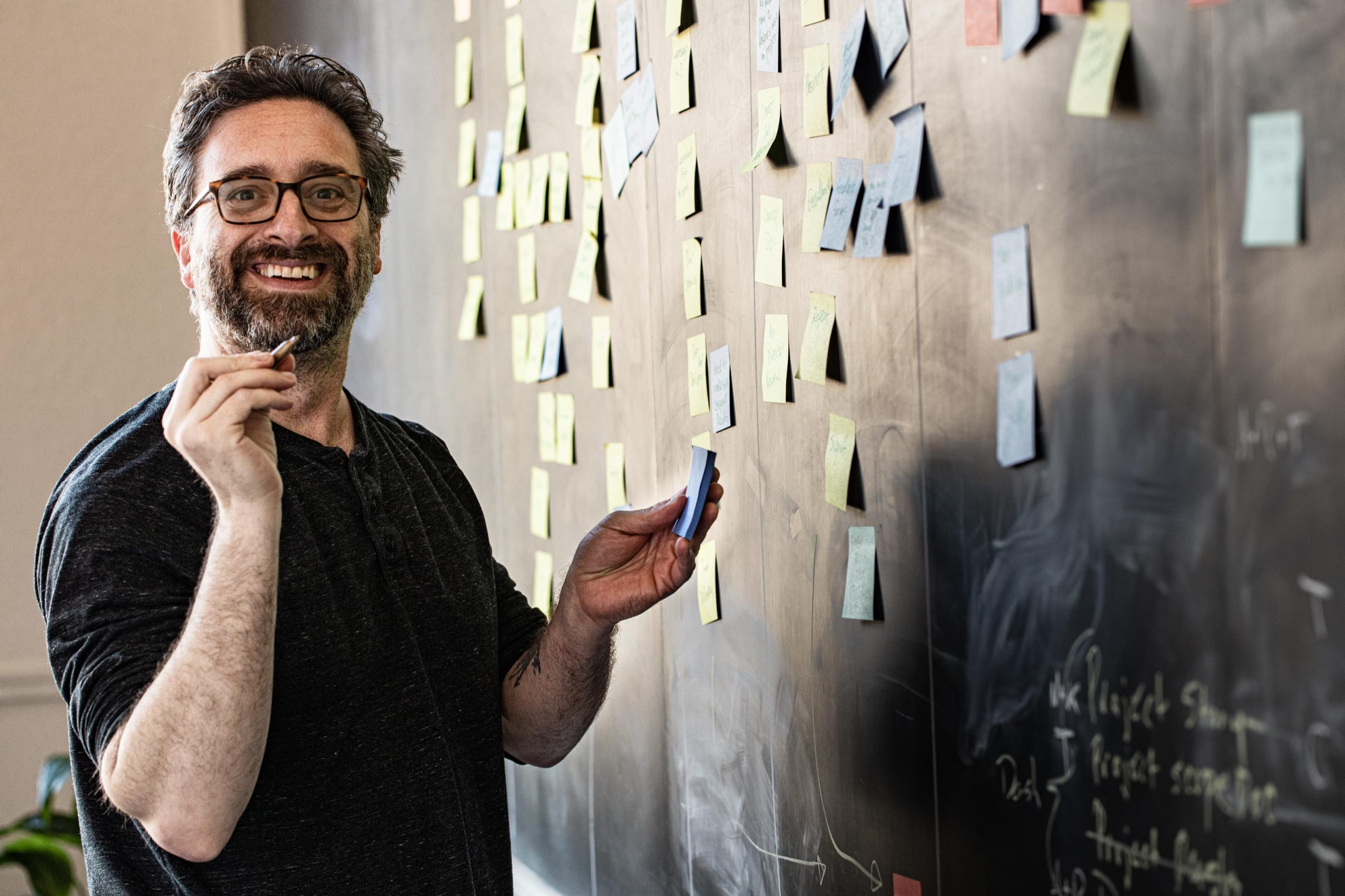 Chris Bolton of Diviner standing in front of board with sticky notes, doing web strategy work in Portland office